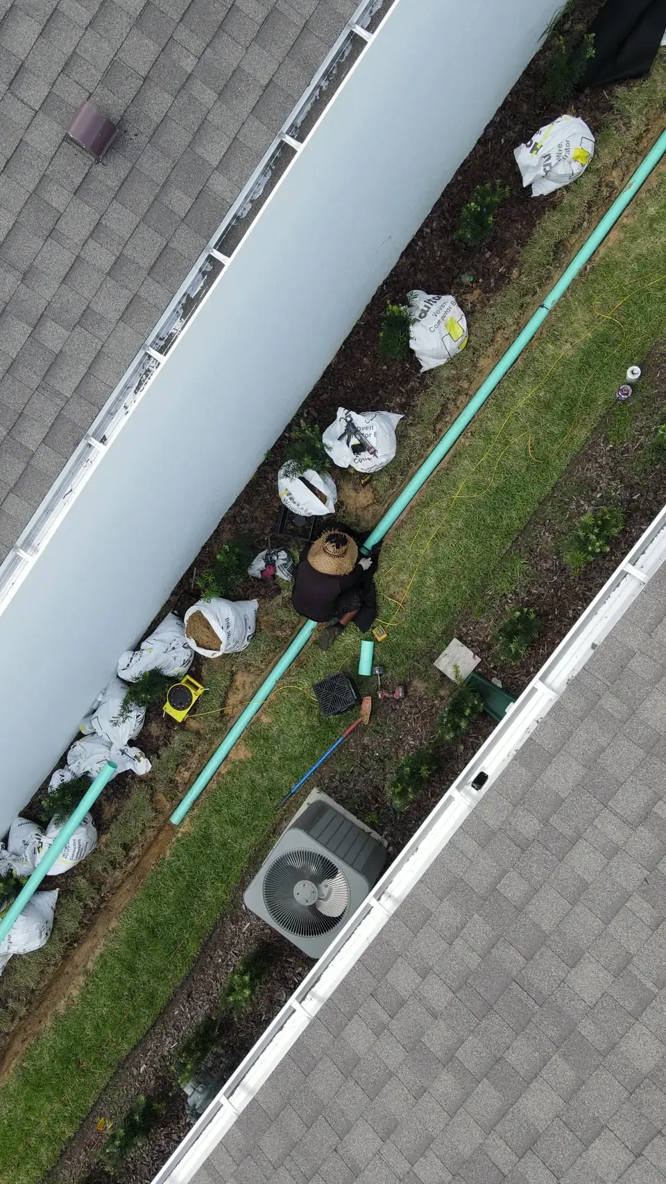 A FAS worker fitting drainage pipe in an open trench between two homes