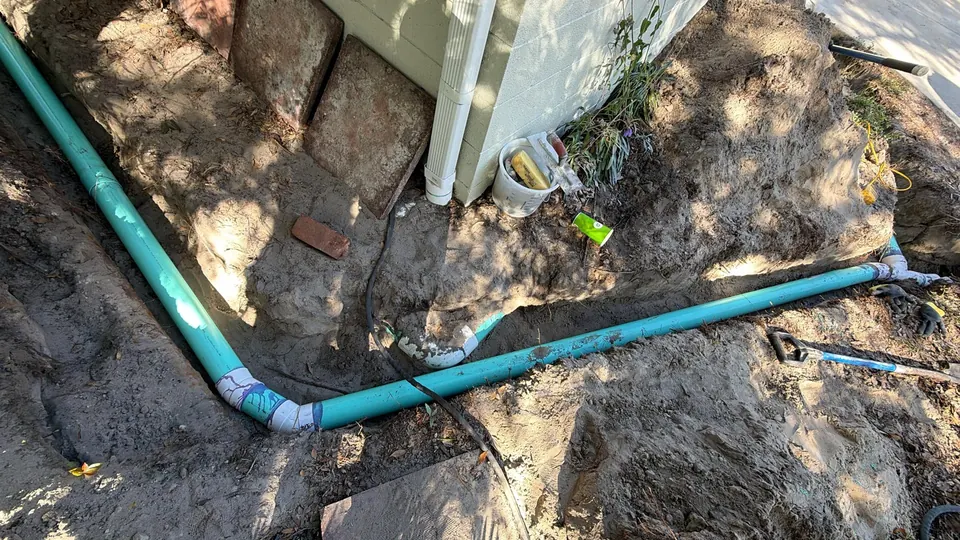 Green drainage pipe and fittings exposed around the corner of a building